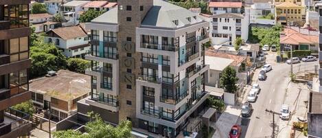 A multi-story building with balconies, a street in front, and surrounding residential buildings.