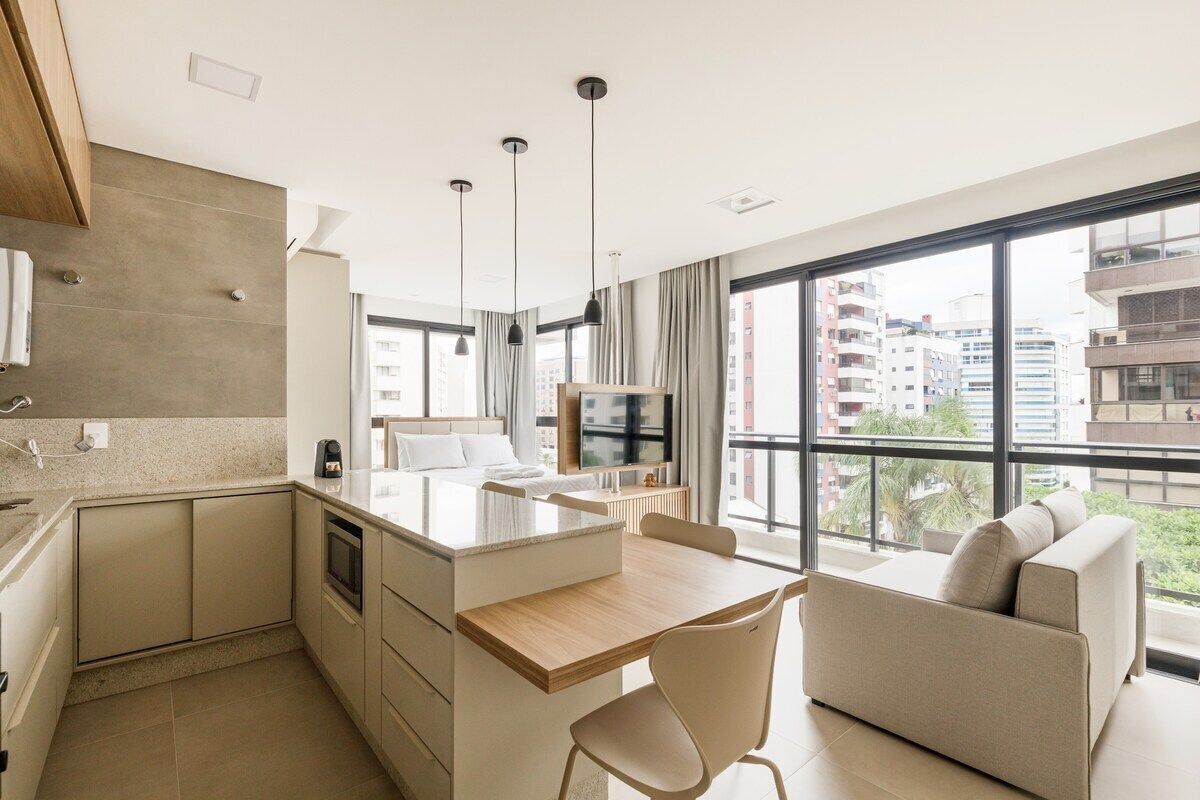A modern apartment with a kitchen, dining area, and a sofa by a large window with a city view.