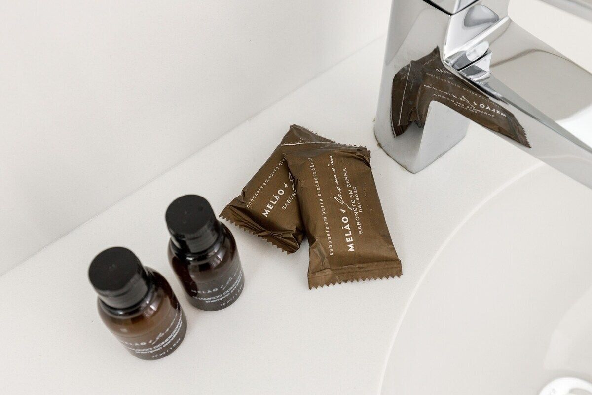 A bathroom sink with two bottles and three soap bars.