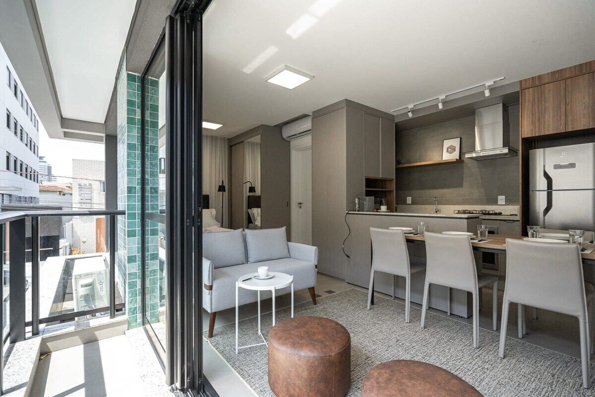 Een modern appartement met balkon, kitchenette, eethoek en woonruimte.
