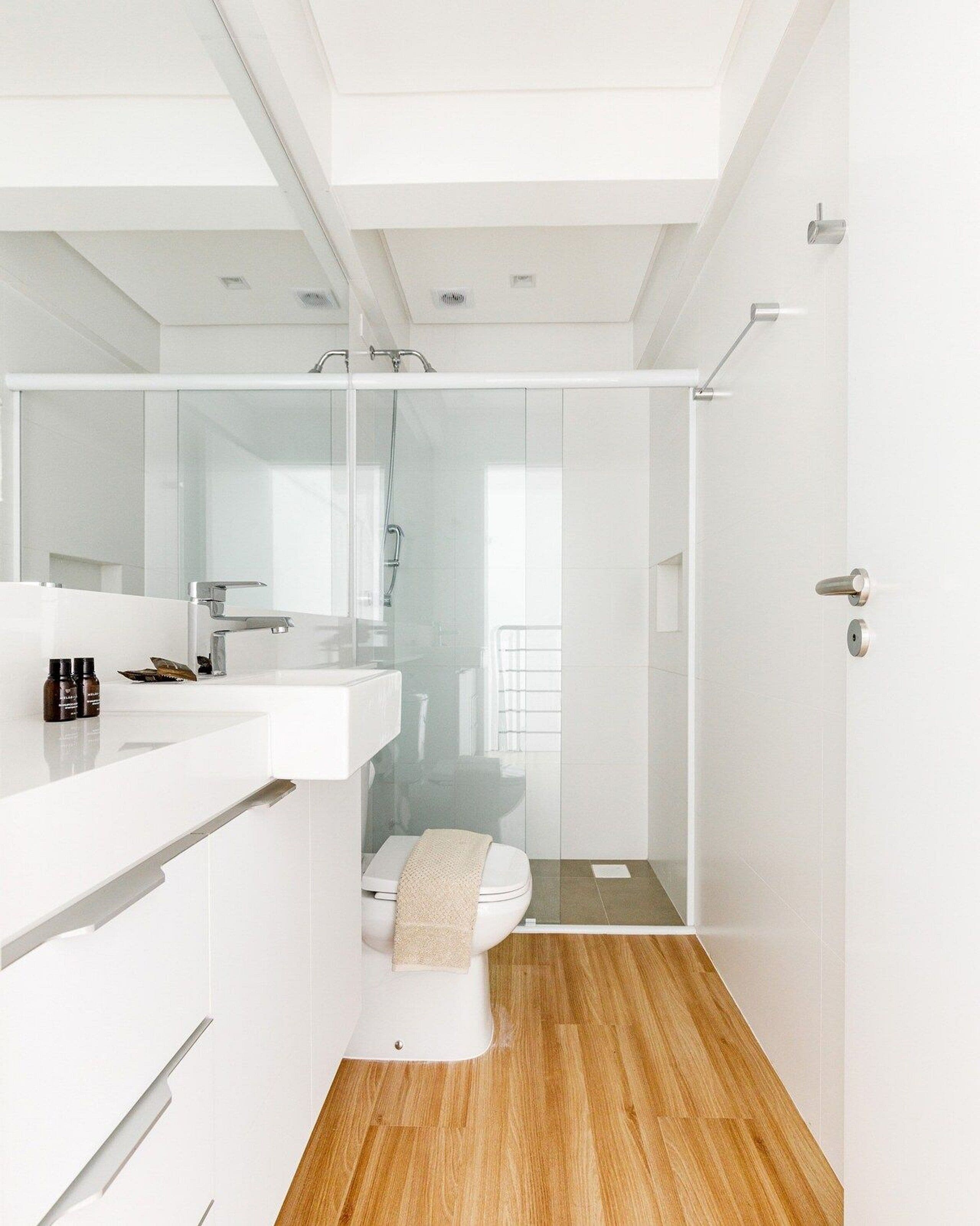 Un baño moderno con cabina de ducha de vidrio, un lavamanos blanco y un inodoro.