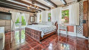 A spacious bedroom with a large bed, a wooden dresser, and a desk.