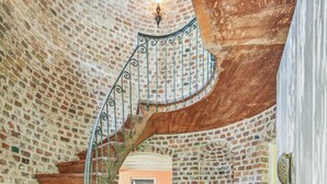 A spiral staircase with a brick wall and a circular floor design.