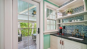 A kitchen with a built-in sink, a coffee maker, and a window overlooking a balcony with outdoor furniture.