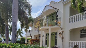 A two-story building with a balcony and a garden in front. - Relaxing, Amazing beach, pool, Cheap cars, quiet area, surfers paradise 3 (Christ Church)