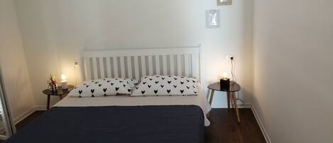 A bedroom with a bed, bedside tables, and a nightstand.