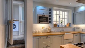 Een moderne keuken met witte kastjes, een ingebouwde oven en een raam boven de gootsteen.