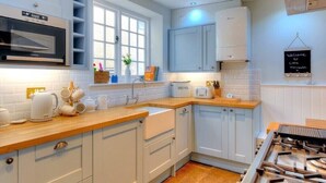 Een moderne keuken met witte kasten, een ingebouwde magnetron, een gasfornuis en een schoolbord.'