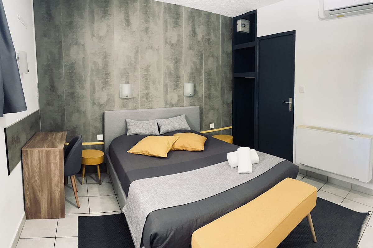 A modern bedroom with a bed, bedside tables, a bench, and a wardrobe.
