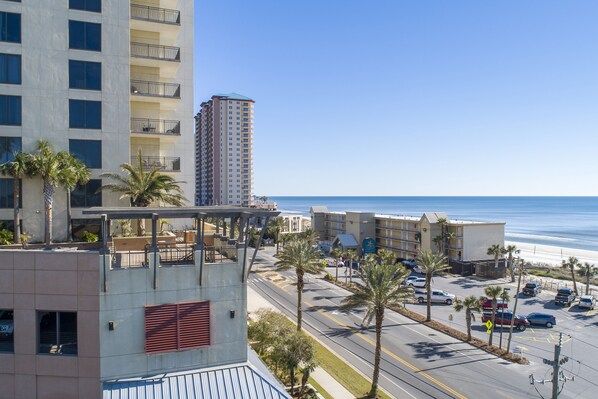 A hotel with a view of the beach, parking lot, and ocean.