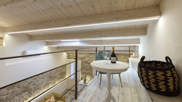 A balcony with a white table, two chairs, a bottle of wine, and a woven basket. - The Theater Suite: Comfort, Position and lots of Light (Alghero)