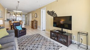 A living room with a sofa, armchair, TV, and patterned rug. - Island Royale 903 by Liquid Life (Gulf Shores)
