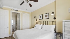 A bedroom with a bed, a ceiling fan, a nightstand, and two wall-mounted lamps. - Island Royale 903 by Liquid Life (Gulf Shores)