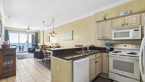A kitchen with a microwave, stove, and a dining area with a view. - Island Royale 903 by Liquid Life (Gulf Shores)