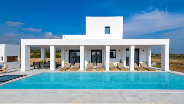 A modern building with a pool, outdoor seating, and a clear blue sky. - Seasand Villa (Rhodes)