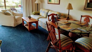 A living room with a sofa, armchair, dining table, and chairs. - Near beach, view tropical plantings from 4th floor privacy, + pickleball courts! (Naples)