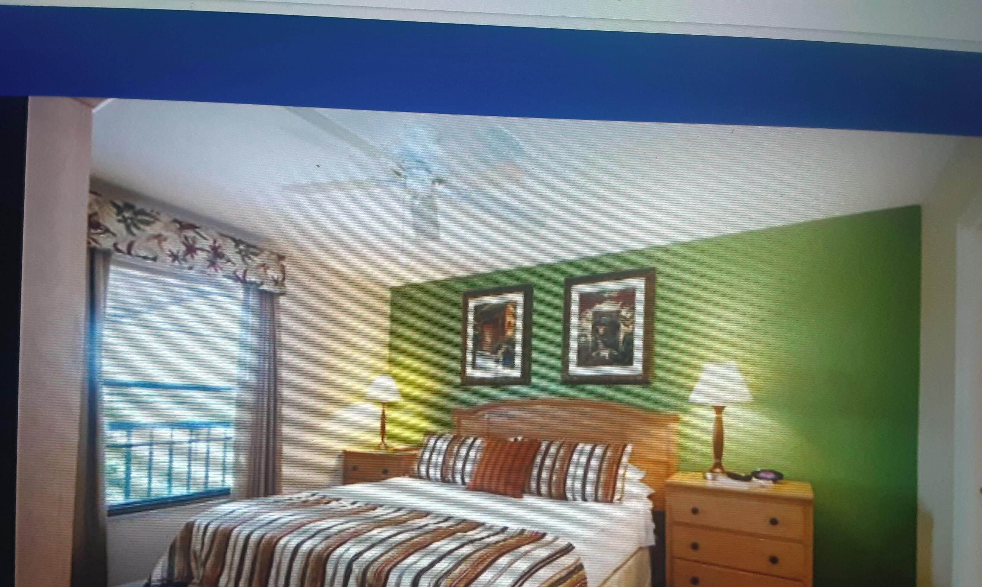 A bedroom with a bed, two bedside tables, a window with curtains, and two framed pictures on the wall.