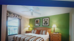 A bedroom with a bed, two bedside tables, a window with curtains, and two framed pictures on the wall. - Near beach, view tropical plantings from 4th floor privacy, + pickleball courts! (Naples)