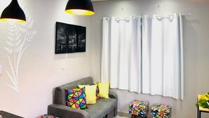 Ein modernes Wohnzimmer mit einem grauen Sofa, bunten Kissen und Pendelleuchten.