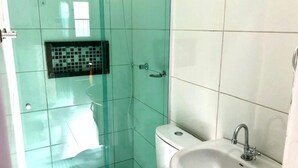 Ein Badezimmer mit Duschkabine aus Glas, Toilette und Waschbecken mit Spiegel.