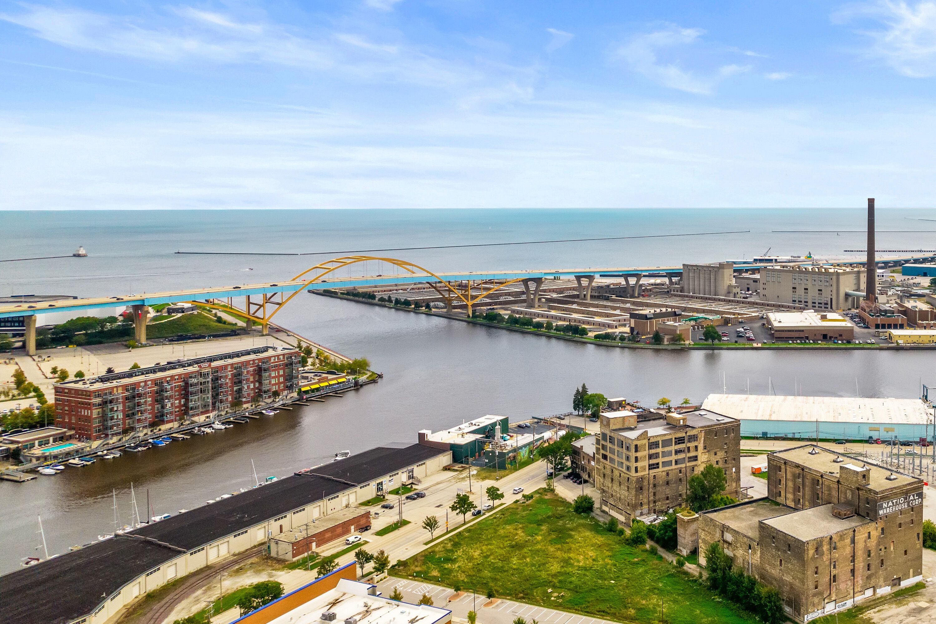 Une zone industrielle traversée par une rivière, avec un pont et des bâtiments, dont un entrepôt.
