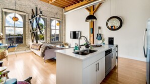 A modern kitchen with a central island, large windows, and a loft-style ceiling. - Cozy 1BD w/ View in Walker's Point, Free Parking (Milwaukee)