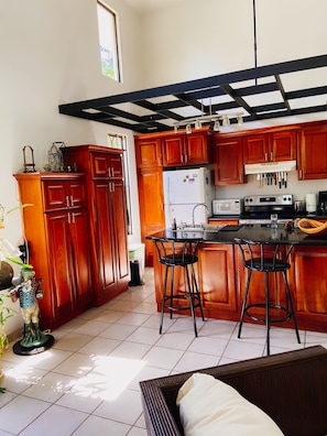 Kitchen features a central island with bar stools, refrigerator, microwave, and stove.