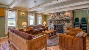 A cozy living room with wooden furniture, a stone fireplace, and a view of the outdoors. - Purity Spring Resort (Madison)