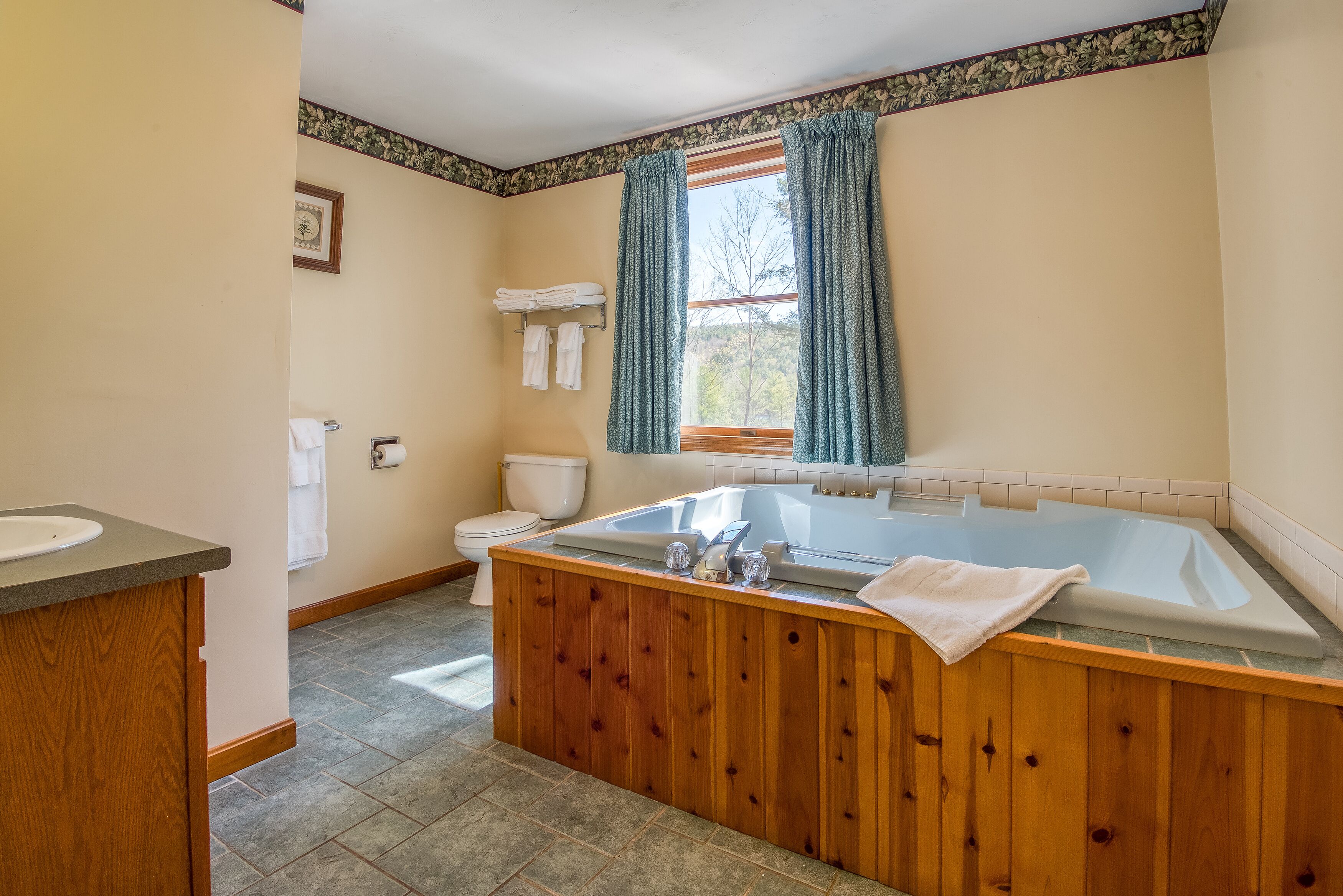 A bathroom with a wooden bathtub, a toilet, and a sink.