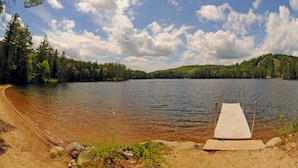 A wooden dock extending into a calm lake surrounded by dense forest. - Purity Spring Resort (Madison)