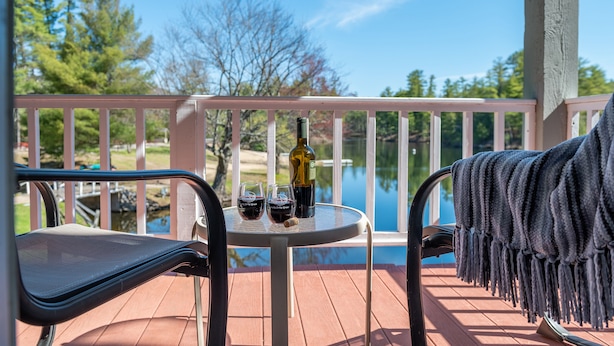A wooden deck with a table and chairs, a bottle of wine, and glasses on it. - Purity Spring Resort (Madison)