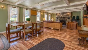 A spacious living room with a wooden dining table, chairs, a sofa, and a stone fireplace. - Purity Spring Resort (Madison)