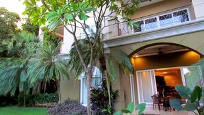 A two-story building with a balcony, a covered outdoor seating area, and lush greenery. - Condominium 206 Matapalo ideal for family trips and work online.  (Tamarindo)