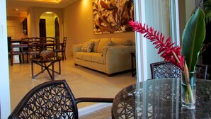 A dining area with a round glass table, wicker chairs, and a dining table with chairs. - Condominium 206 Matapalo ideal for family trips and work online.  (Tamarindo)