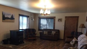 Un salon avec une cheminée, un canapé, un fauteuil et une lampe.