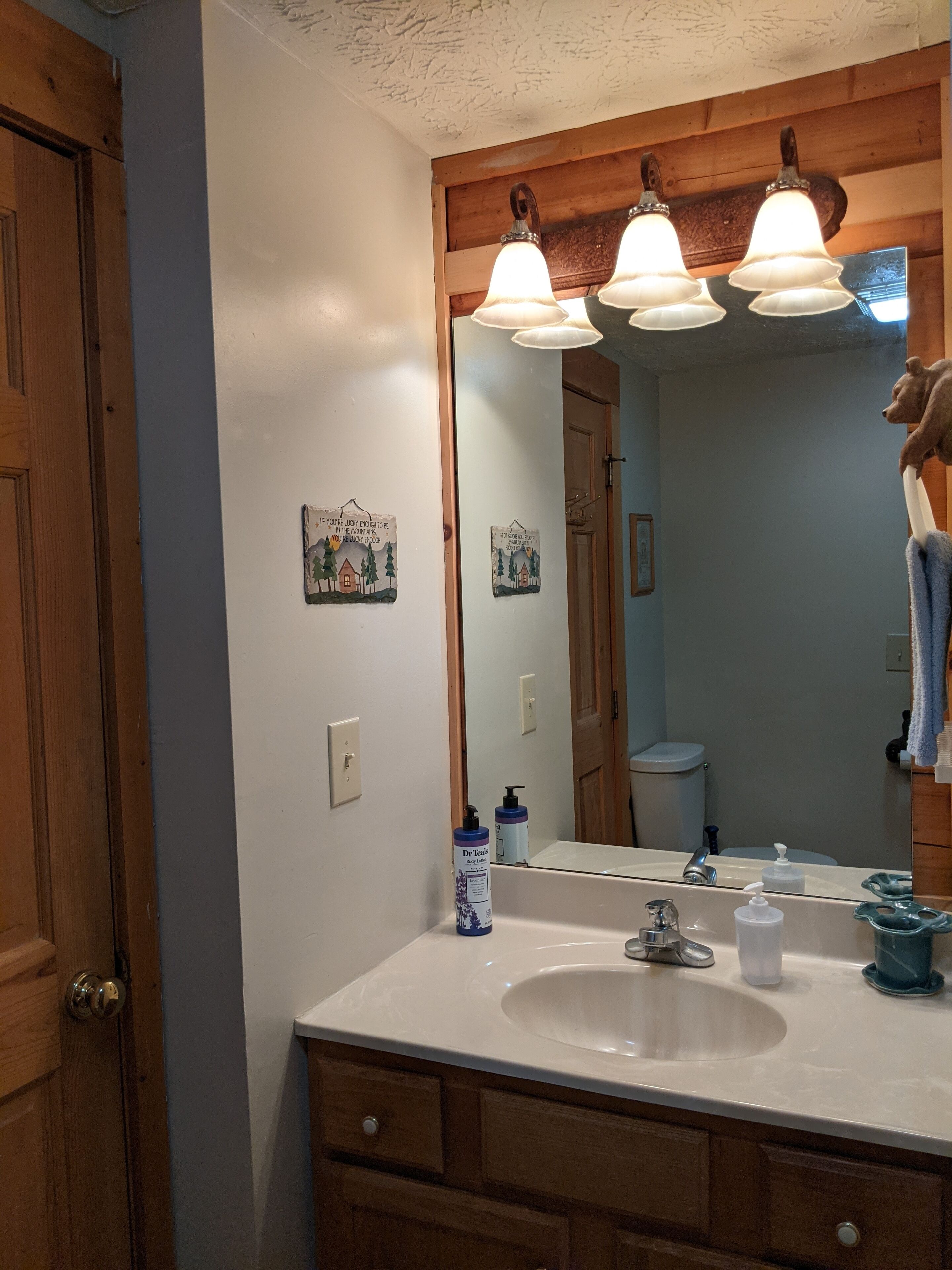 Une salle de bain avec un lavabo blanc, des meubles en bois, un miroir avec un cadre en bois et une serviette accrochée au mur.