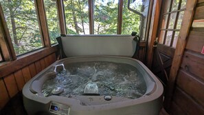 A hot tub with a digital temperature display, surrounded by wooden walls and large windows.