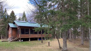 A cabin with a metal roof, wooden exterior, and a porch. - Beautiful retreat in the Adirondack Park (Malone)
