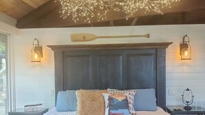 Un dormitorio con techo de madera, una cama con muchas almohadas y faroles en la pared.