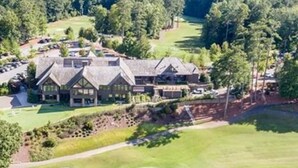 Un campo de golf con un club de campo y un estanque.