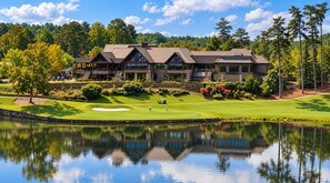 A golf course with a clubhouse, a pond reflecting the buildings, and a clear sky. - Romantic Retreat in the Treetops of Big Canoe with Hot Tub & Stunning Views! (Jasper)