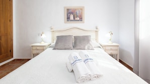 A neatly made bed with two pillows, a framed painting above, and two bedside tables with lamps. - Chalet Rocio 1 Conil de la Frontera by Ruralidays (Cádiz)