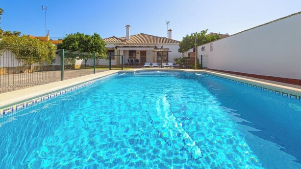 A rectangular swimming pool with clear blue water, surrounded by a white wall and a fence. - Chalet Rocio 1 Conil de la Frontera by Ruralidays (Cádiz)