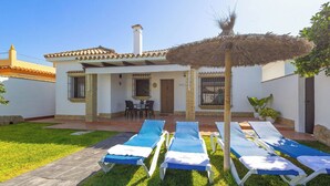 A villa with a patio, outdoor seating, and sun loungers. - Chalet Rocio 1 Conil de la Frontera by Ruralidays (Cádiz)