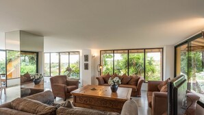 Een ruime woonkamer met een grote houten salontafel, bruine banken en een televisietoestel.