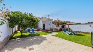 A house with a tiled roof, a small garden, and two blue lounge chairs. - Chalet Rocio 2 Conil de la Frontera by Ruralidays (Cádiz)