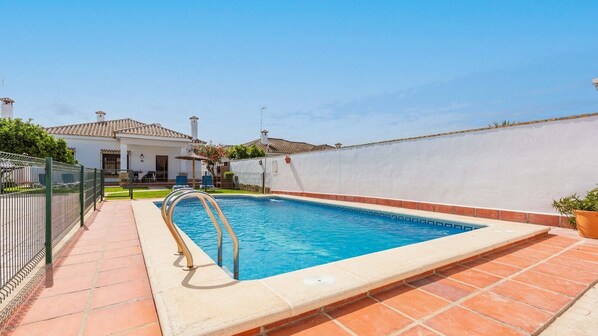 A swimming pool with a metal ladder, surrounded by a white wall and a tiled deck. - Chalet Rocio 2 Conil de la Frontera by Ruralidays (Cádiz)