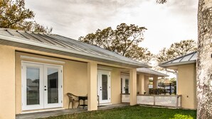 A two-story building with a covered patio area, a lawn, and a tree in the background.