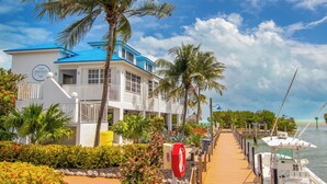 Een hotel aan de kust met een blauw dak, een receptie en een steiger met boten.