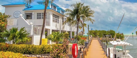 A coastal hotel with a blue roof, a guest registration area, and a dock with boats.